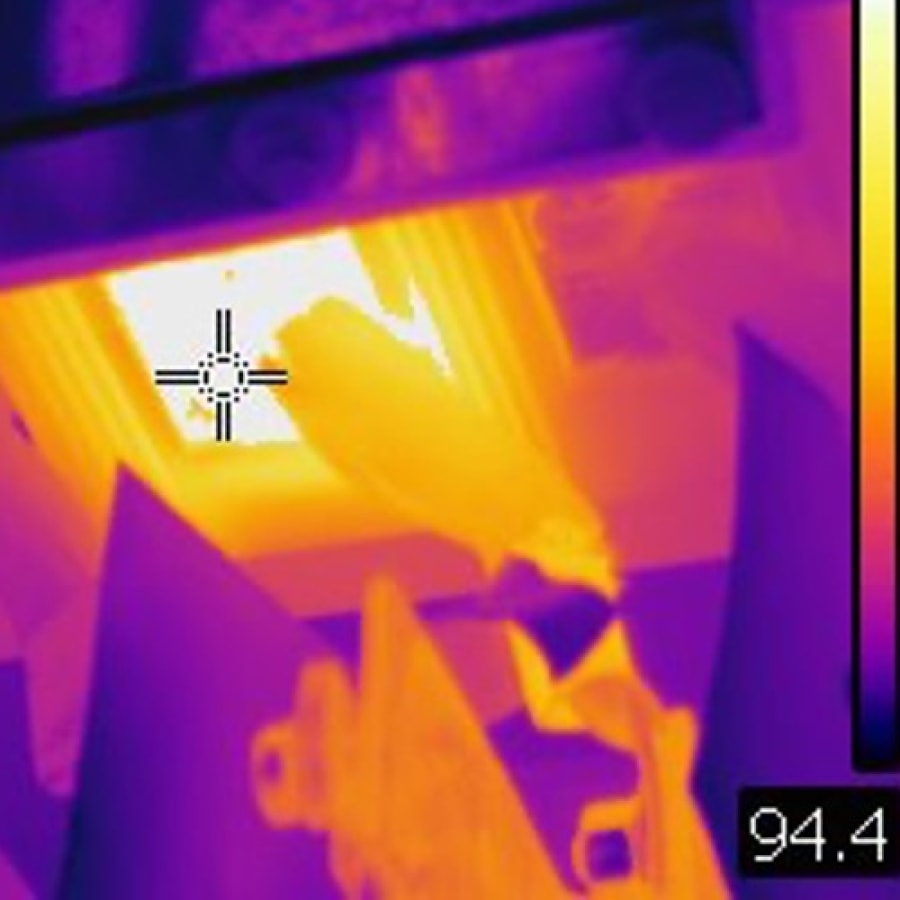 Thermal image showing a component with bright yellow and white areas indicating high heat, surrounded by cooler blue and purple areas; temperature reading in the bottom right corner shows 94.4.